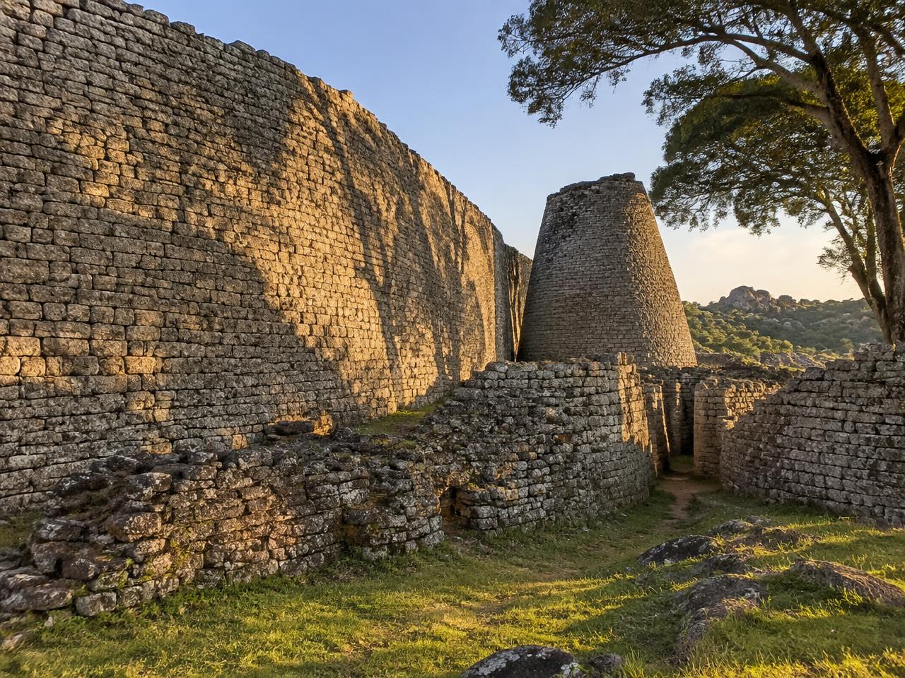 Geschwungene Trockensteinmauer aus Granit mit kegelförmigem Turm in grünem Grasland