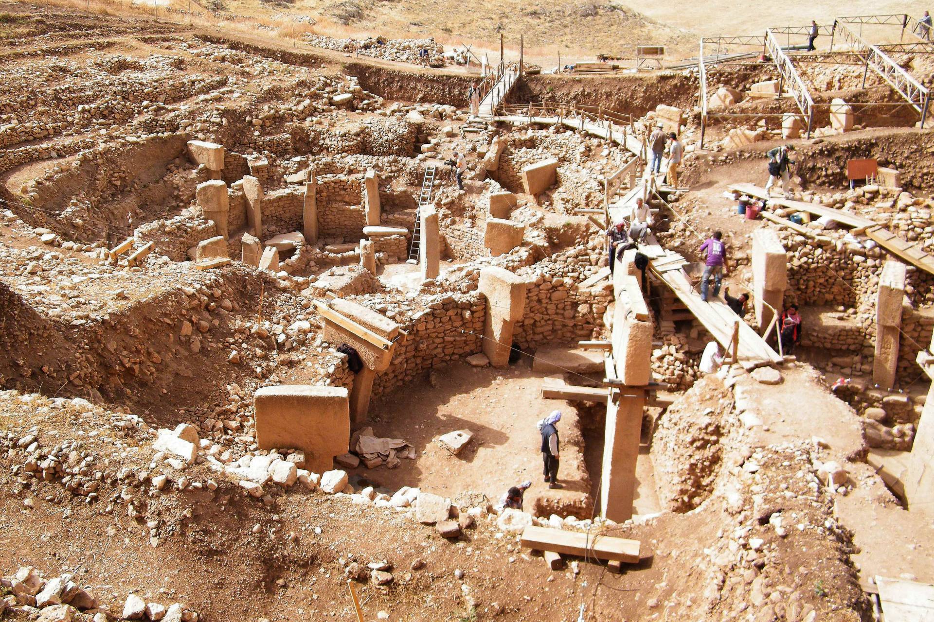 Blick auf die kreisförmig ausgerichteten T-förmigen Stelen und Mauerreste in der Ausgrabungsstätte Göbekli Tepe